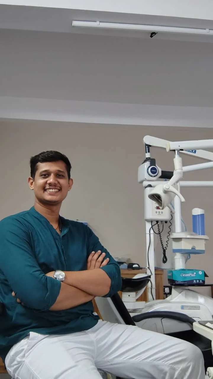 Dr. Dharmendar Jadav seated beside dental equipment at the clinic.
