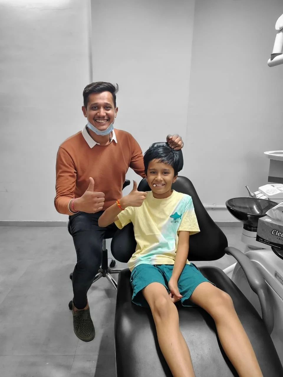 A child patient seated beside the dentist at the clinic.